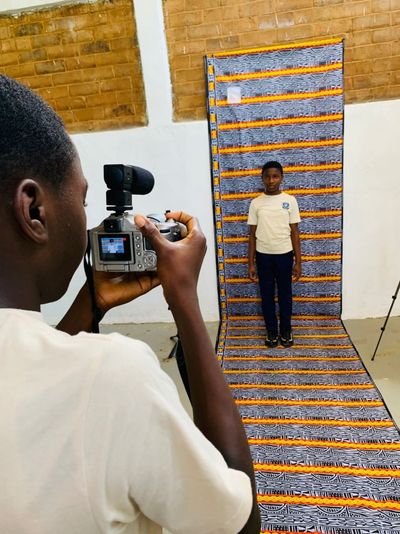 A student photographing a classmate against a patterned backdrop