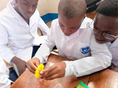 Students in lab coats assembling a small motor and circuit at a workbench
