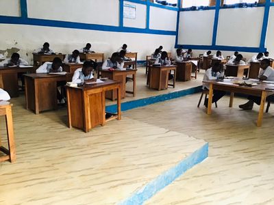 Students writing at wooden desks in a bright classroom