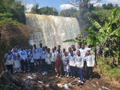 A class in uniform standing in front of a waterfall on a field trip