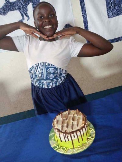 A student smiling behind a birthday cake