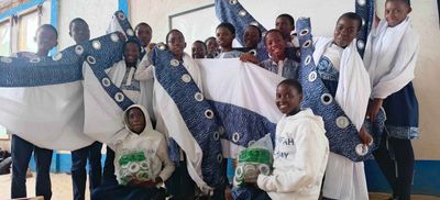 Students holding up patterned curtains they have made